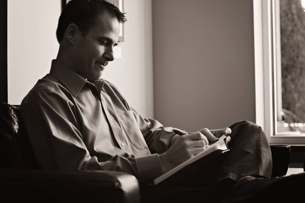 A black and white photo of Steve writing in a note book