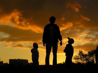 A father playing outside at sunset with his two children