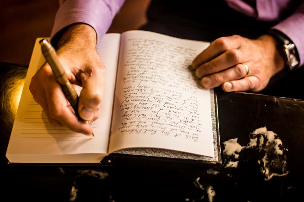 A person using a calligraphy pen to write in cursive in a book